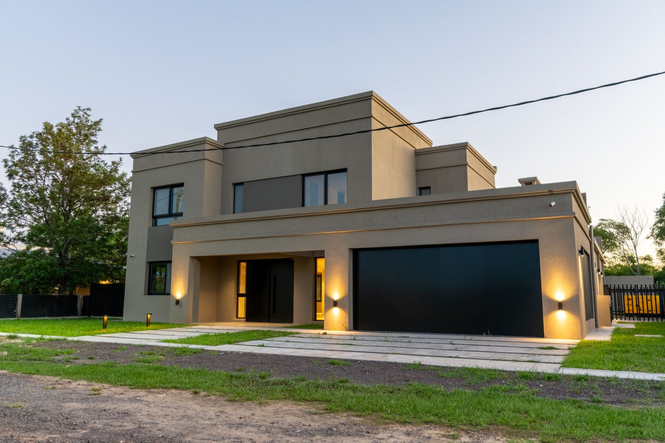 Vivienda CFL en Corrientes: frente de dos plantas iluminado al atardecer